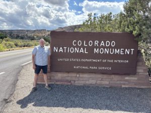 Paul Aspelin standing in front of the sign for the east entrance of the Colorado National Monument