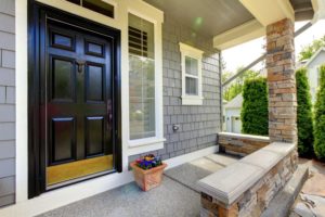 front porch with black door and stone wall