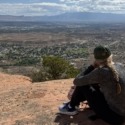 10-Day Grand Junction Challenge Megan Jirele Writer sitting on slickrock looking out over the valley towards Grand Junction