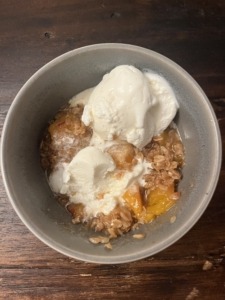 homemade peach cobbler with vanilla ice cream in a bowl