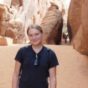Megan standing in front of a slot canyon on a hike in Arches National Park