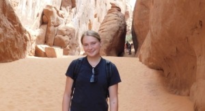 Megan standing in front of a slot canyon on a hike in Arches National Park