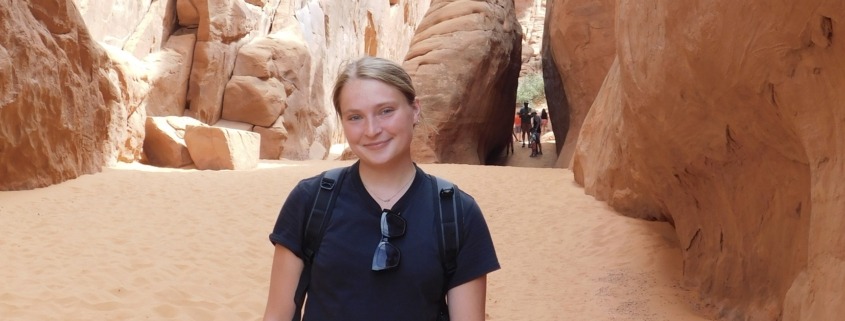Megan standing in front of a slot canyon on a hike in Arches National Park