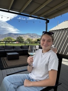 Megan sitting in a chair with a glass of wine at the Carboy Winery in Palisade