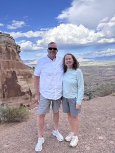 Paul and Michelle Aspelin standing at the top of Serpents Trail with Grand Junction in the distance