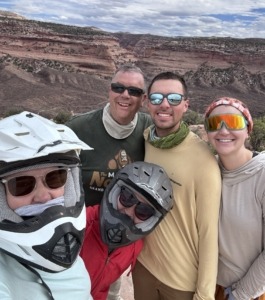 Group photo of Michelle Paul Megan and more with helmets on with Colorado River Valley in the background